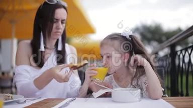 妈妈在户外餐馆里喂淘气的女孩汤